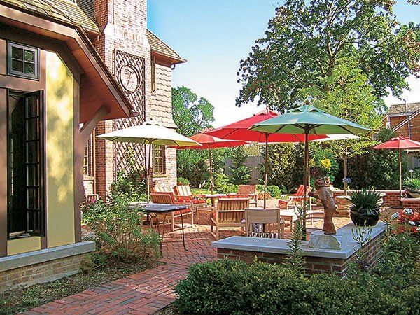 A patio with tables and umbrellas in front of a house