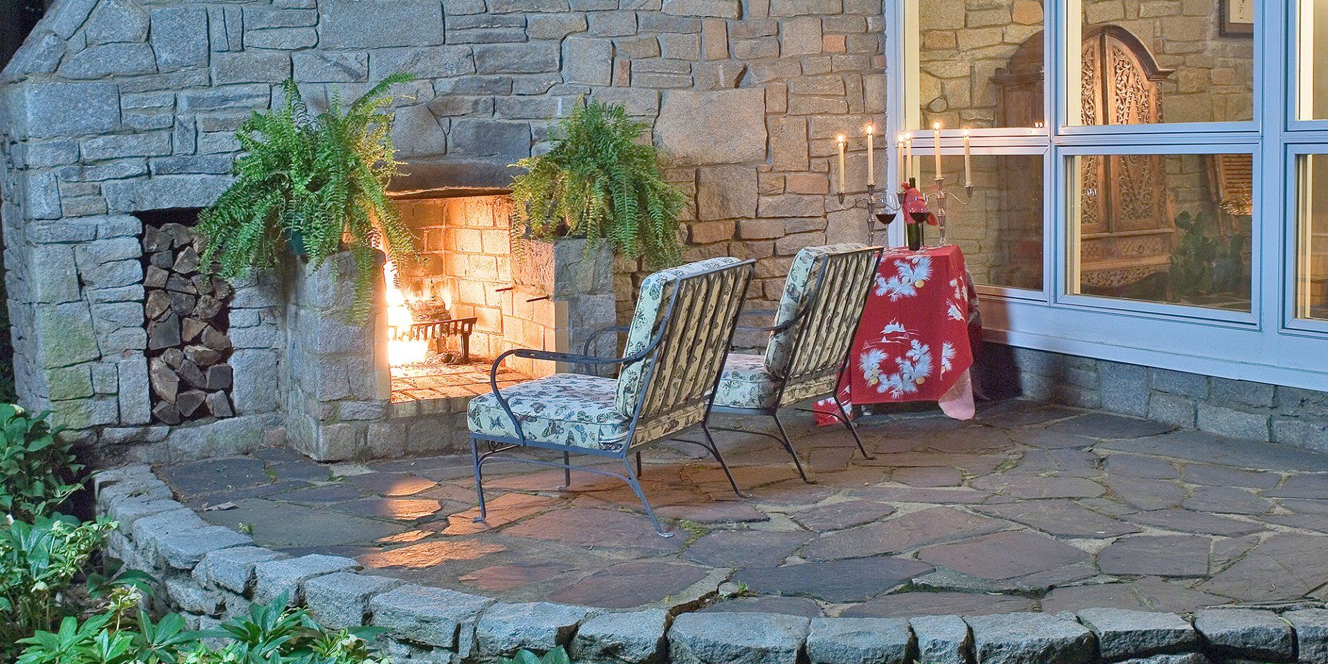 A patio with a fireplace and chairs in front of it