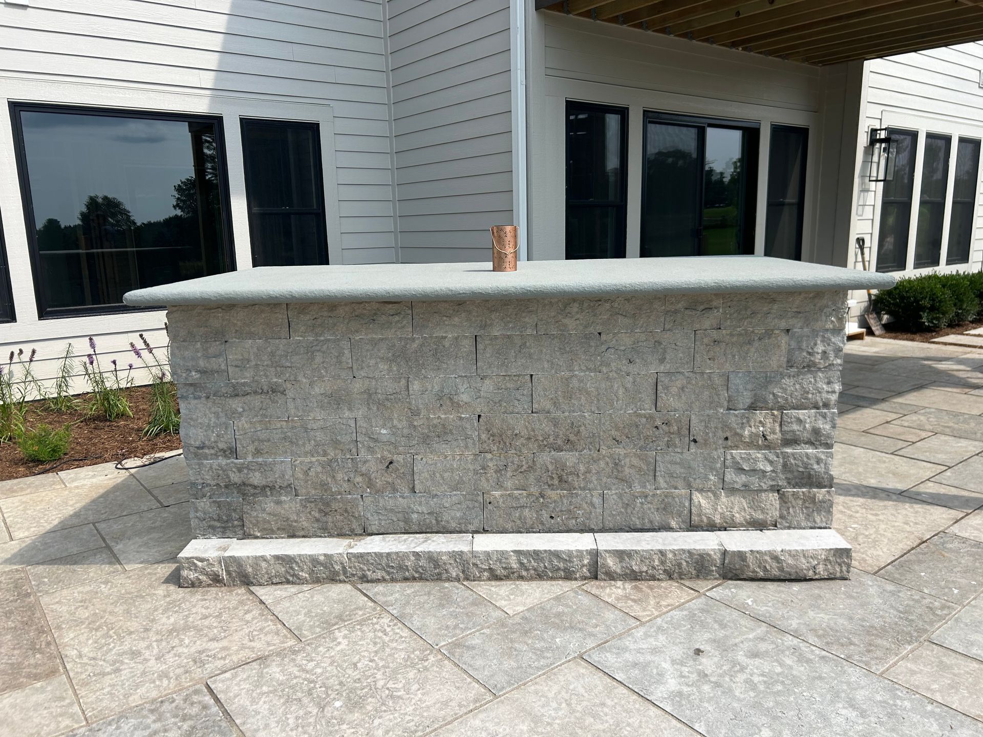 A brick counter top is sitting on a patio in front of a house