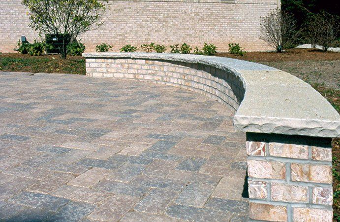 A curved stone wall with a brick pillar in front of it