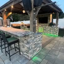 A gazebo with a bar and stools underneath it.