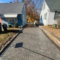 A brick driveway leading to two houses on a sunny day.