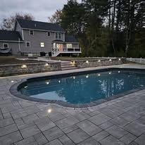There is a large swimming pool in front of a house.