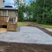 A gazebo is sitting on top of a concrete patio next to a house.