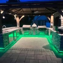 A large outdoor kitchen with green lights underneath it.