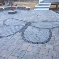A patio with a butterfly design on it and a fire pit.