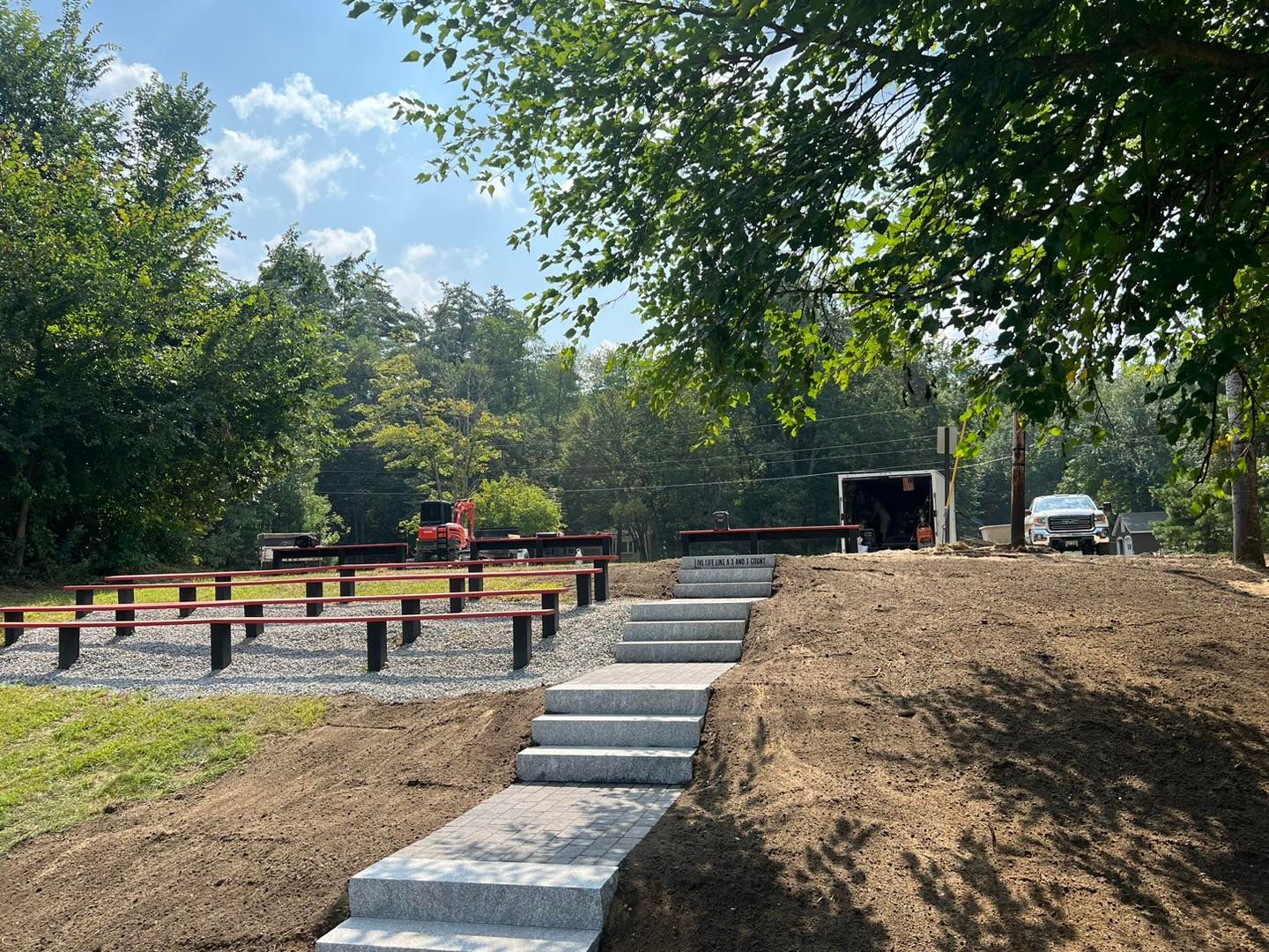 A concrete walkway leading to a picnic area in a park.