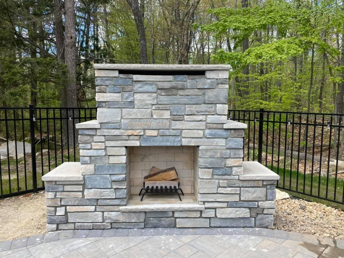A stone fireplace with a fence in the background
