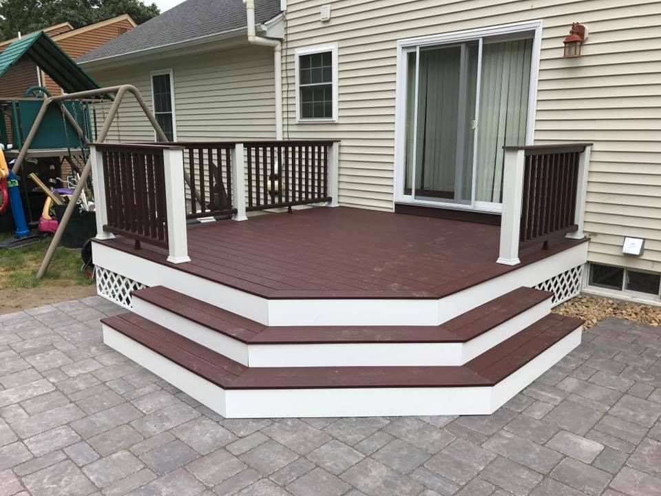 A deck with stairs and a railing in front of a house.
