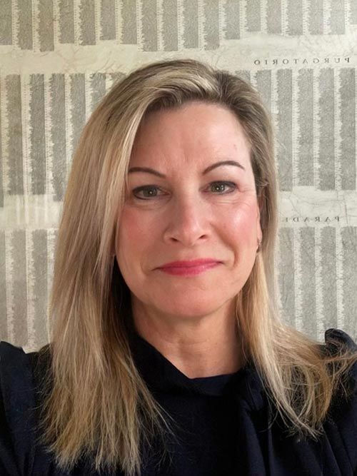 A woman with long blonde hair is wearing a black shirt and smiling.