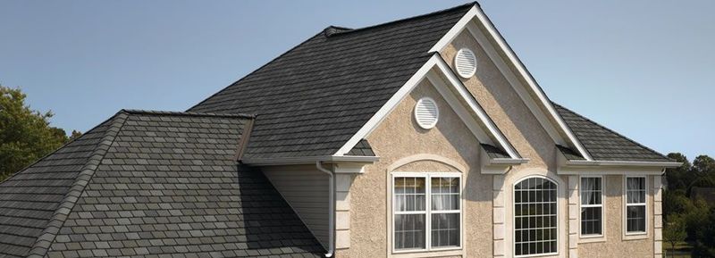 House with dark gray roof against a light blue sky.