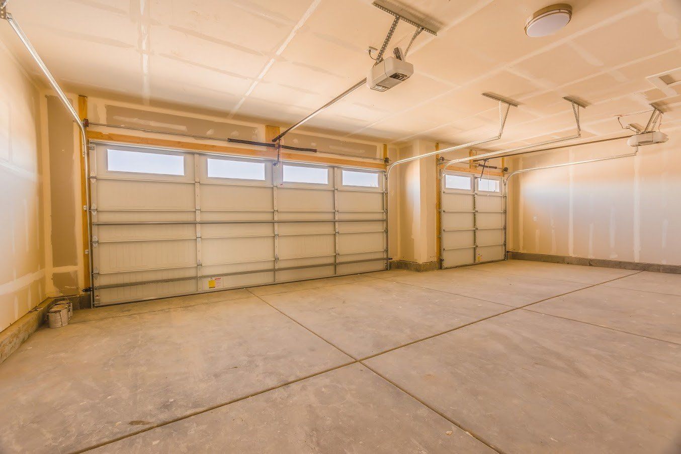 Empty beige garage with two overhead doors.