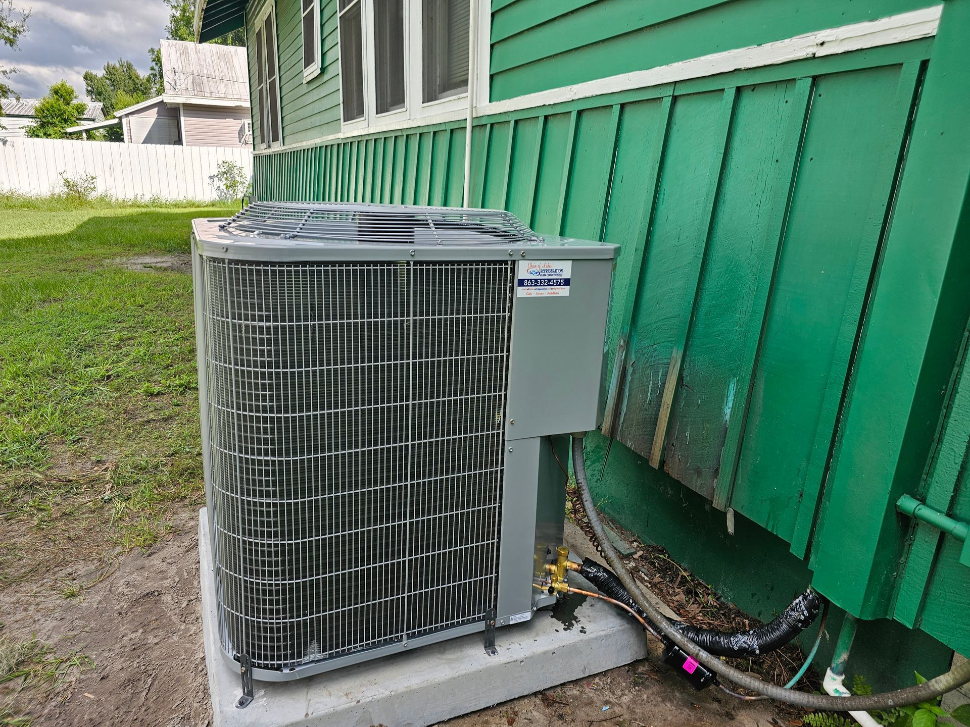 An air conditioner is sitting on the side of a greenhouse.