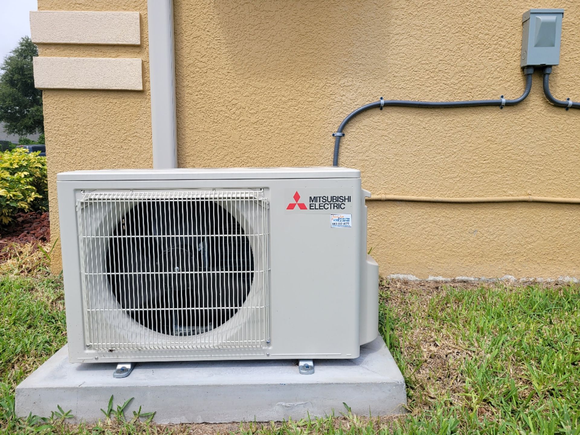 A mitsubishi air conditioner is sitting on the side of a building.