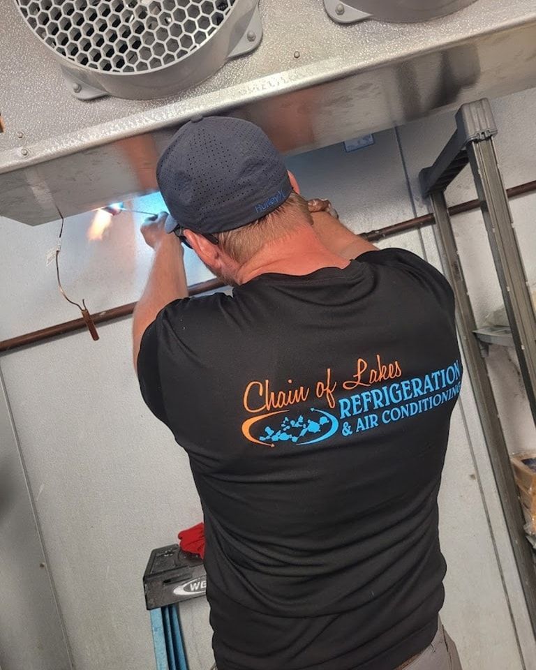 A man in a black shirt is working on a refrigerator.