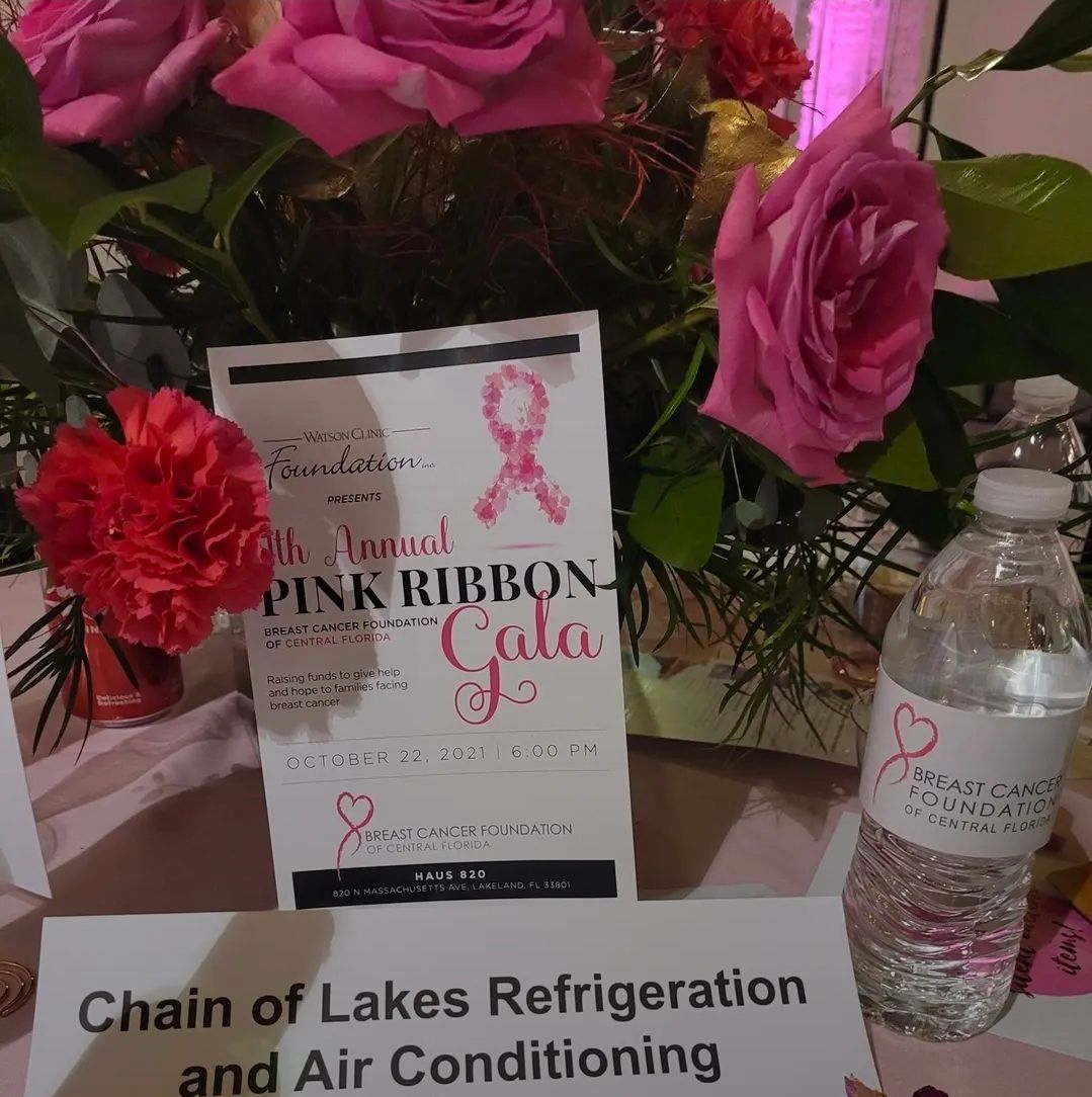 A table setting with pink roses, a bottle of water, and a sign for the Annual Pink Ribbon Gala featuring a pink ribbon.