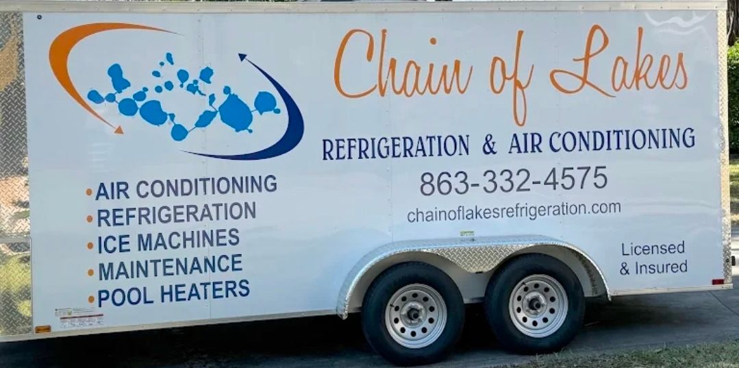 A white service trailer for Chain of Lakes Refrigeration & Air Conditioning, displaying contact info and services.