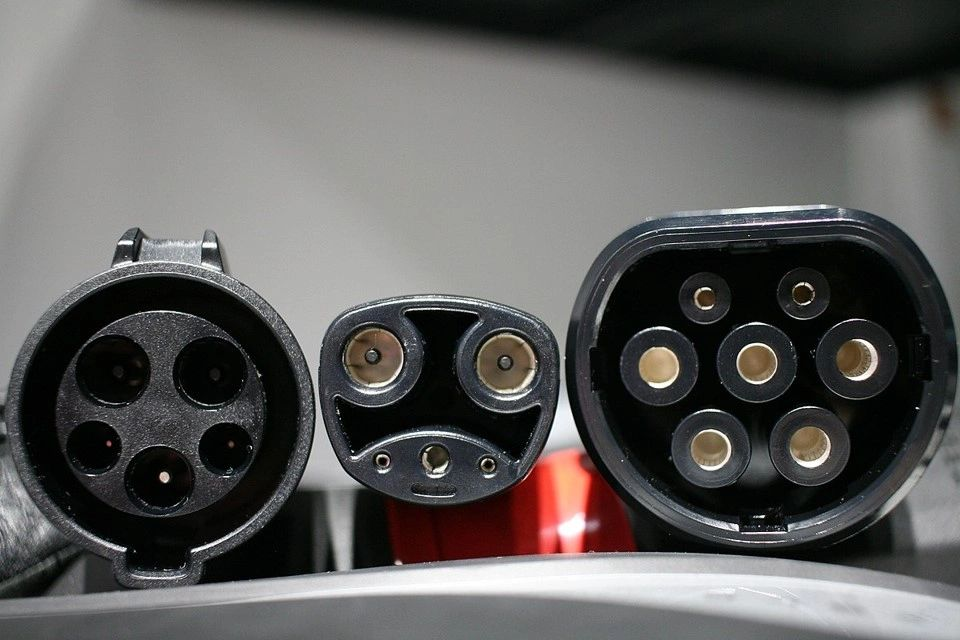 Three different types of plugs are lined up on a table.