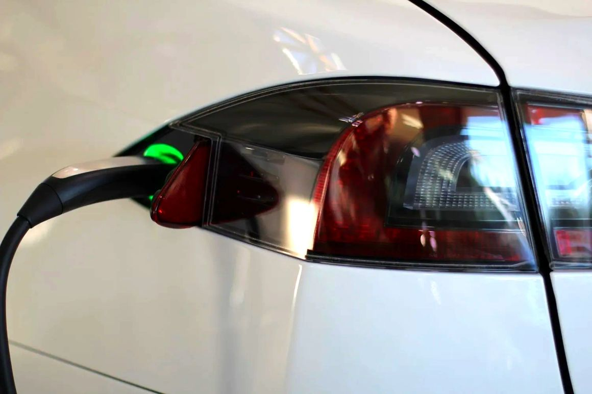 A white electric car is being charged at a charging station.