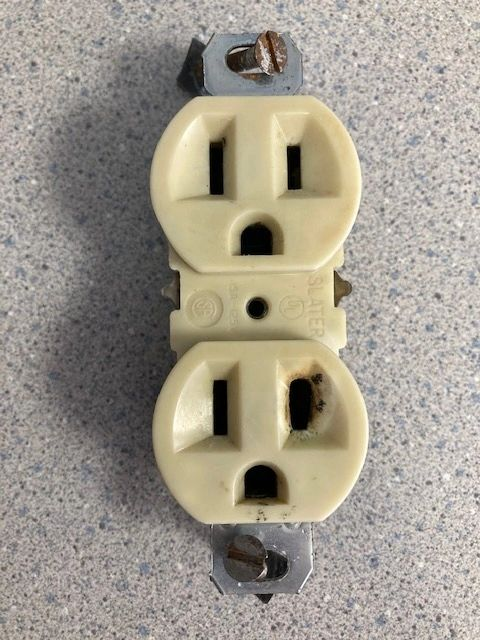 A close up of a yellow electrical outlet on a counter top