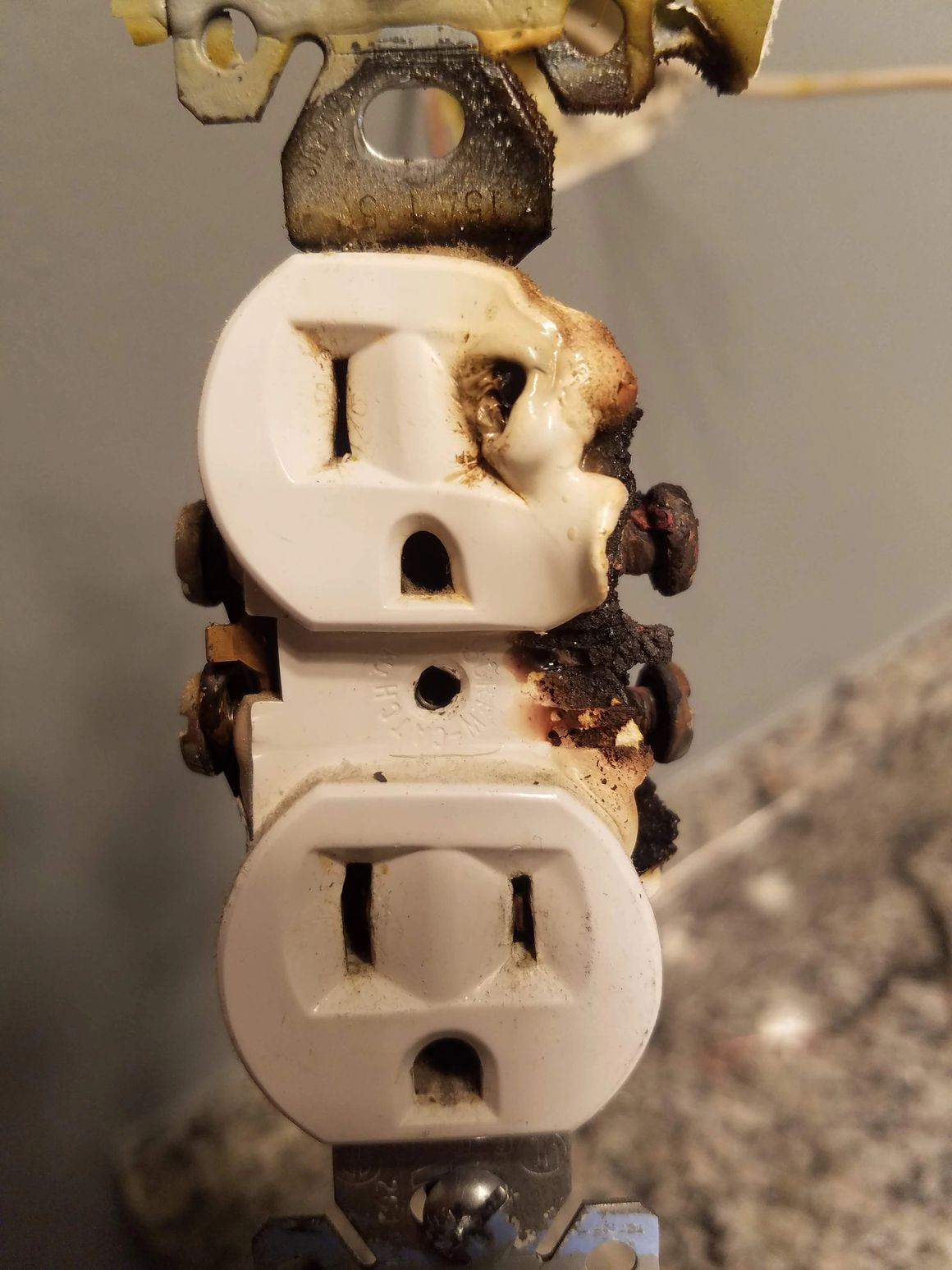 A burnt electrical outlet with visible charring on the right side of the top socket.