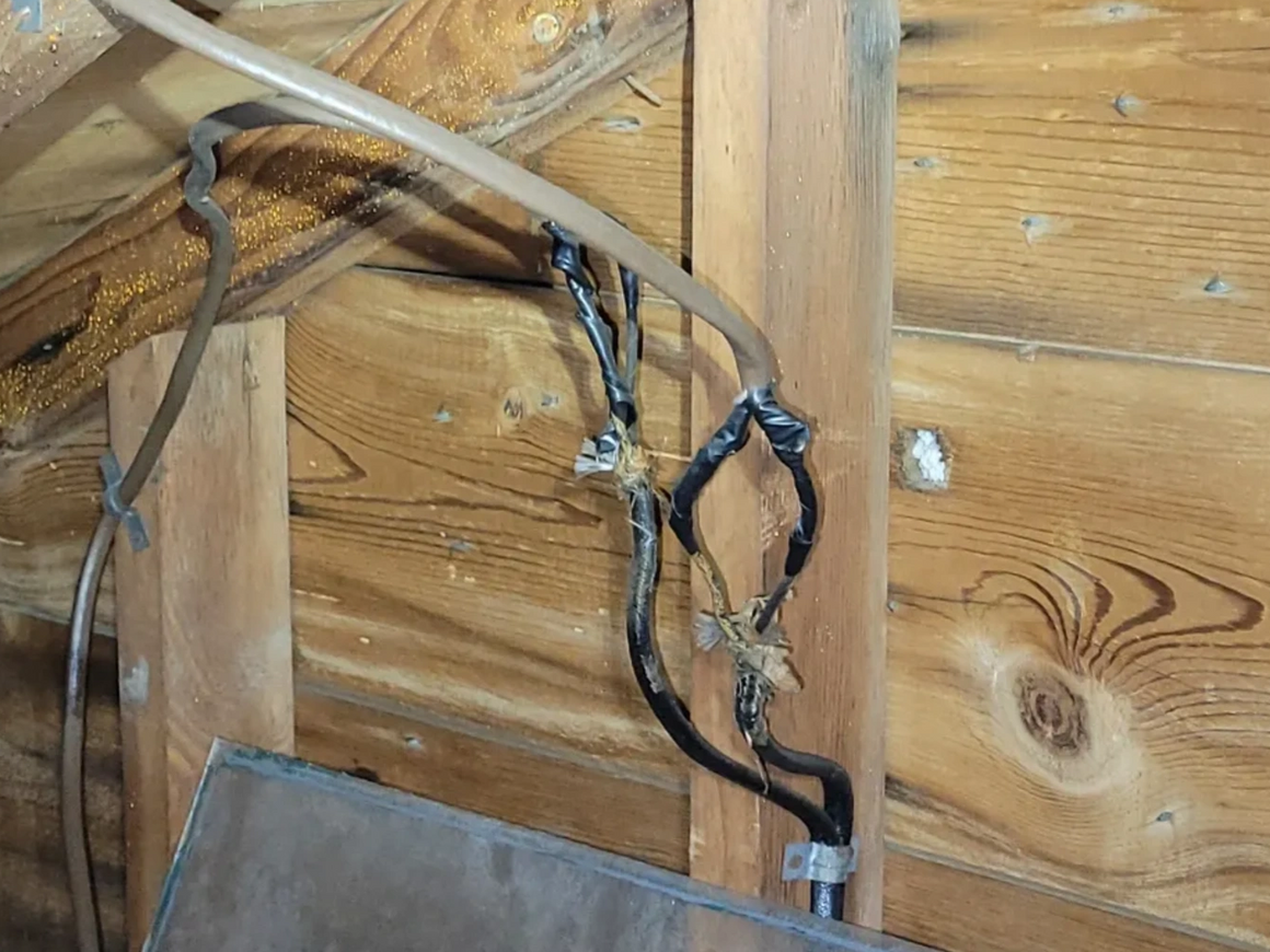 A bunch of wires are hanging from a wooden wall.