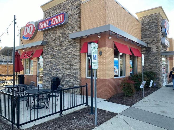 Dairy Queen Grill & Chill storefront with outdoor seating and red awnings on a sidewalk corner