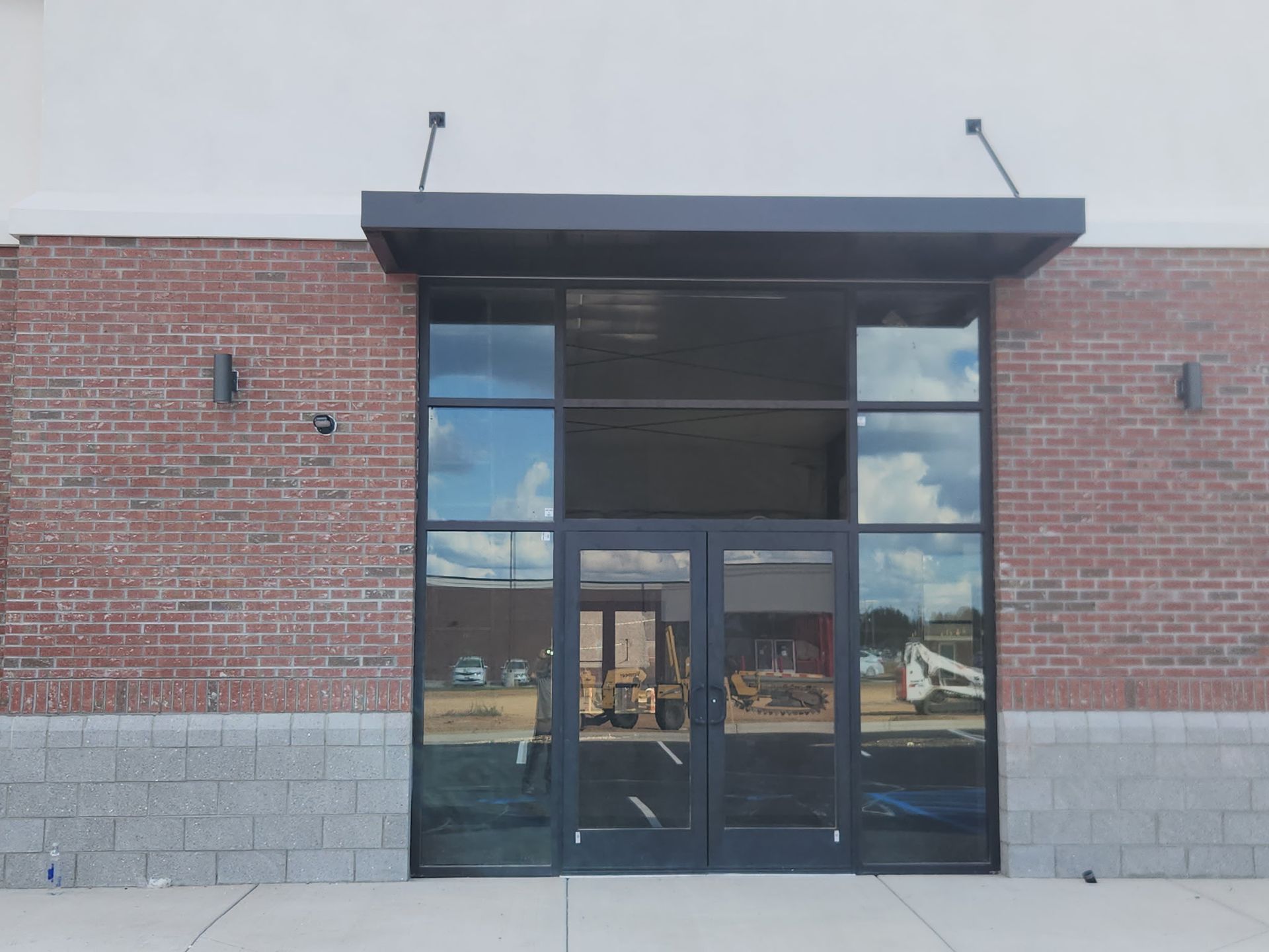 Brick storefront entrance with dark glass doors and windows under a black awning