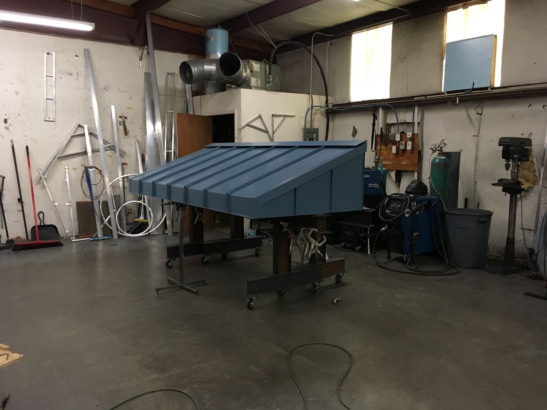 Blue metal rooftop structure in a workshop with tools and equipment around it