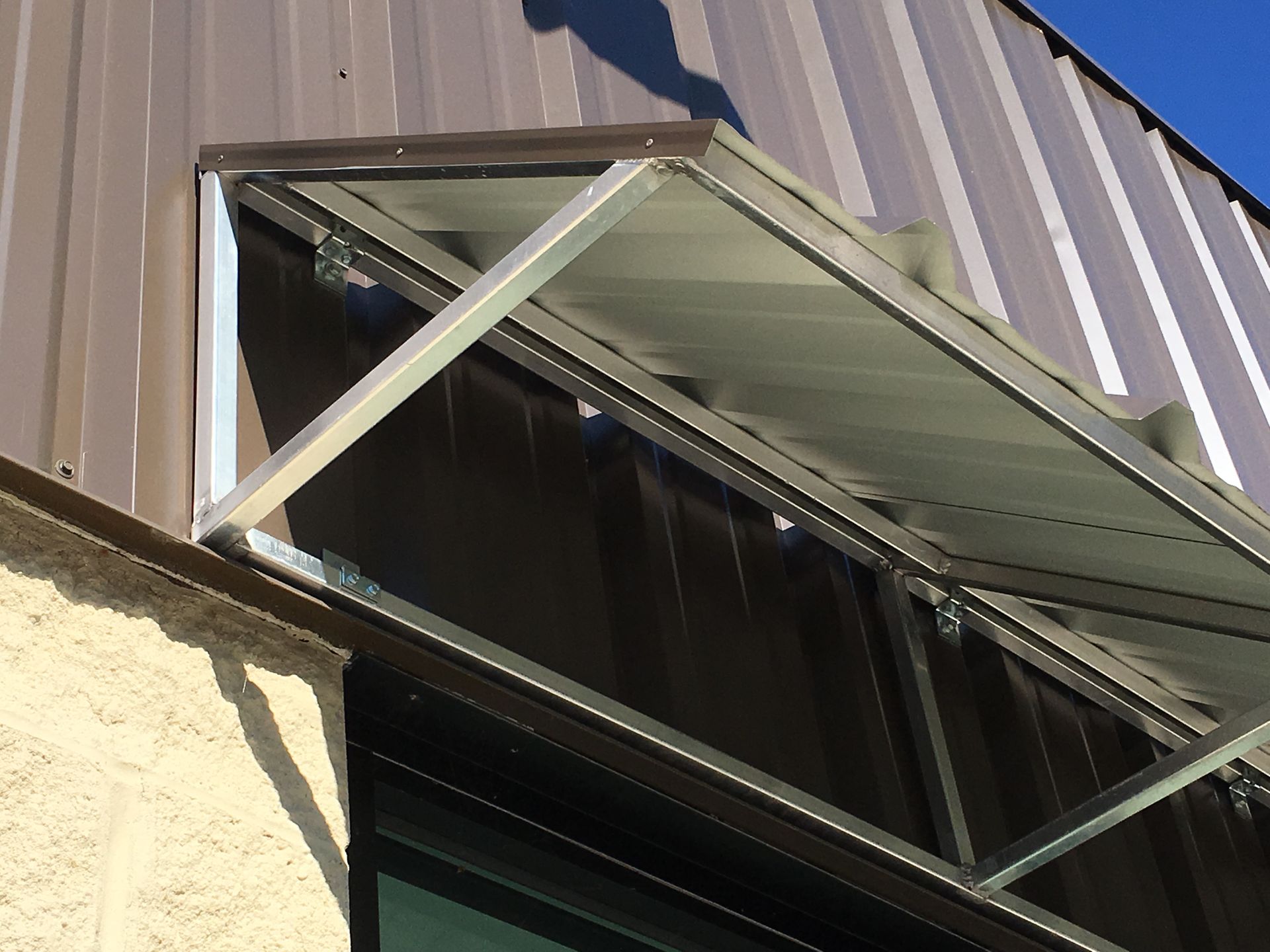 Open metal-framed window awning on a corrugated building wall
