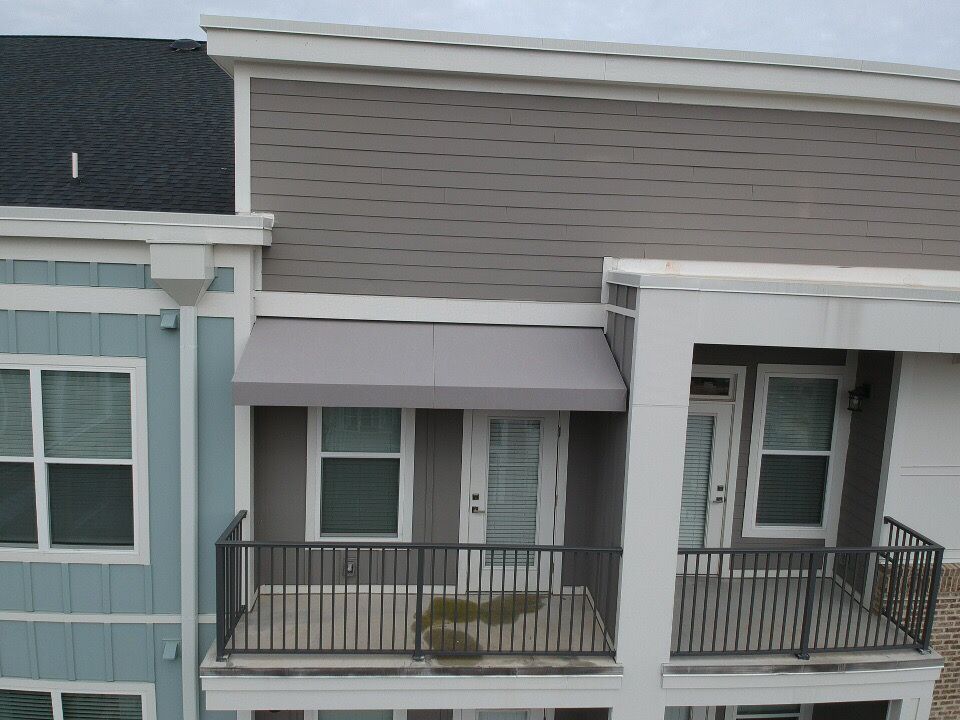 Row of townhouse facades with small front porches, railings, and gray, white, and blue siding