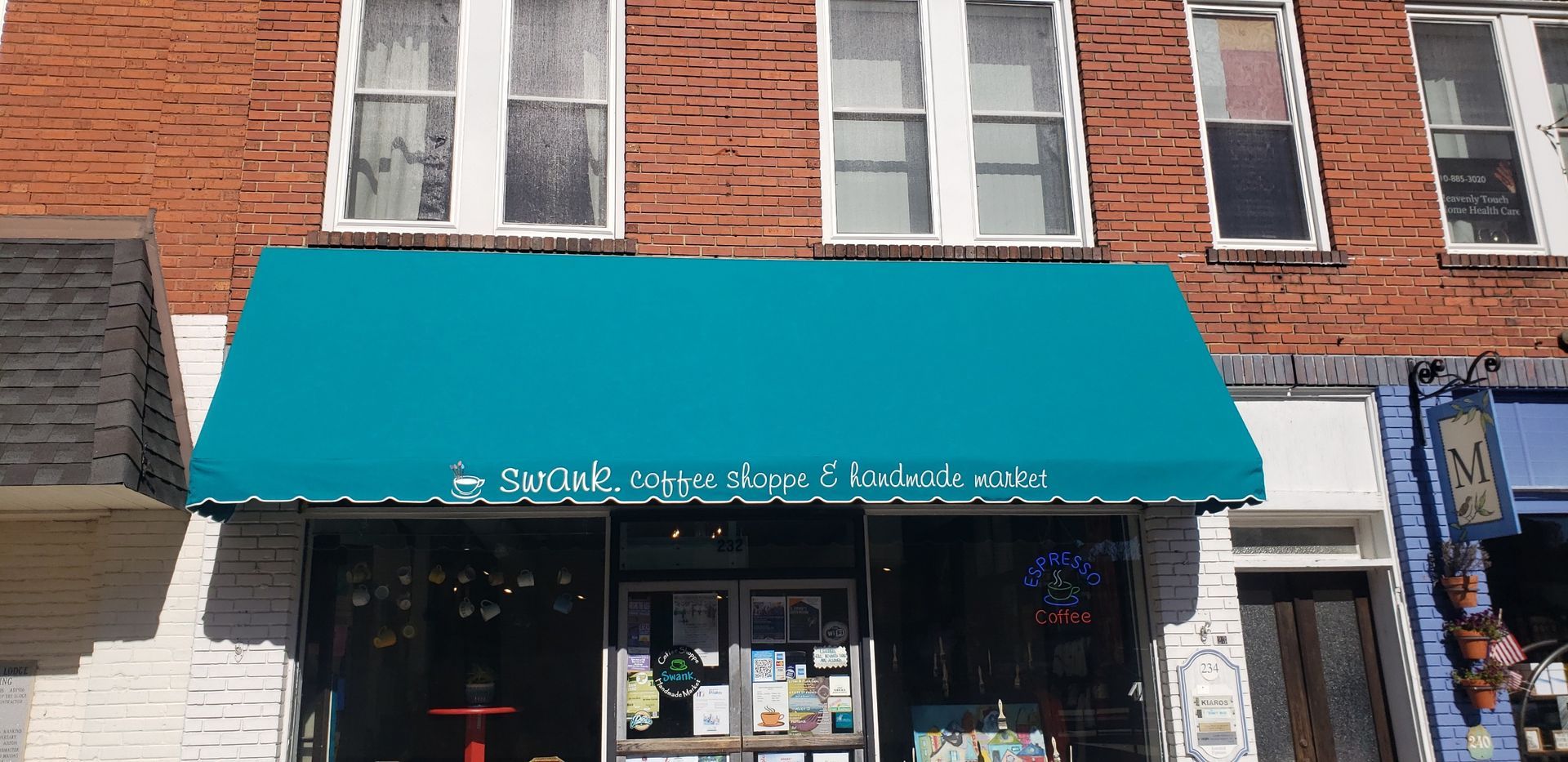 Storefront with teal awning on a brick building and shop windows below