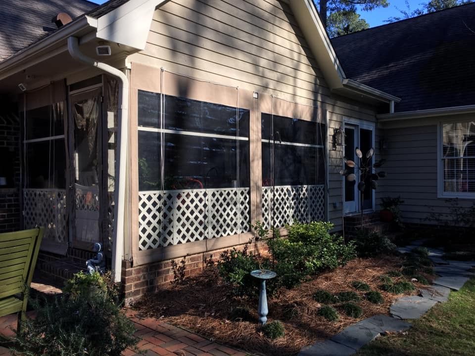 House exterior with screened porch, beige siding, white lattice, and a small garden path in front