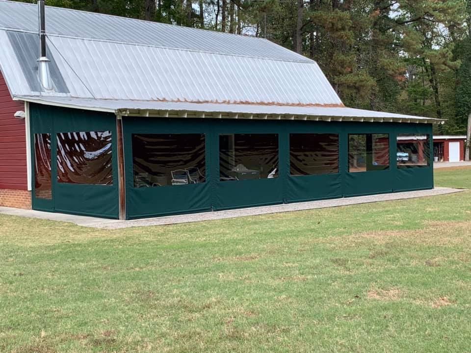 Green pavilion with a metal roof and open sides in a grassy park area