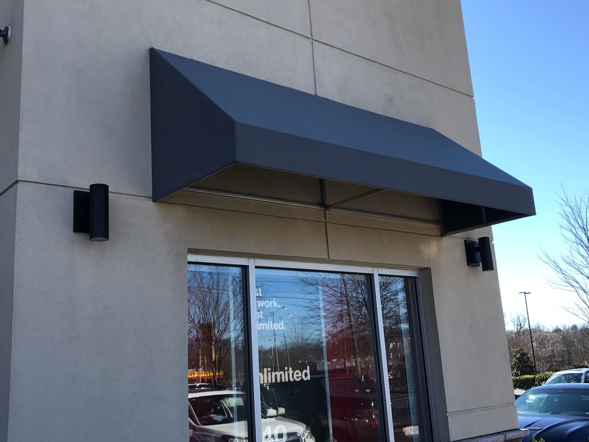 Black awning over a glass storefront entrance on a beige building
