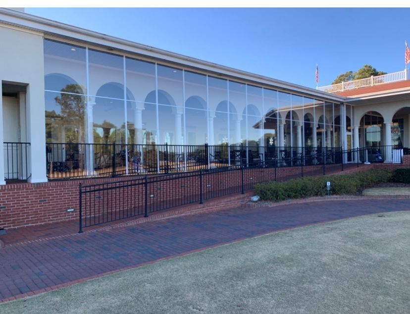 Brick building with large arched windows and a covered patio beside a grassy lawn