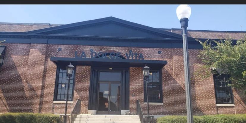 Brick building entrance with dark awning, windows, and a lamppost in front