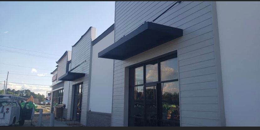 Modern storefronts with gray facades and black awnings along a street.