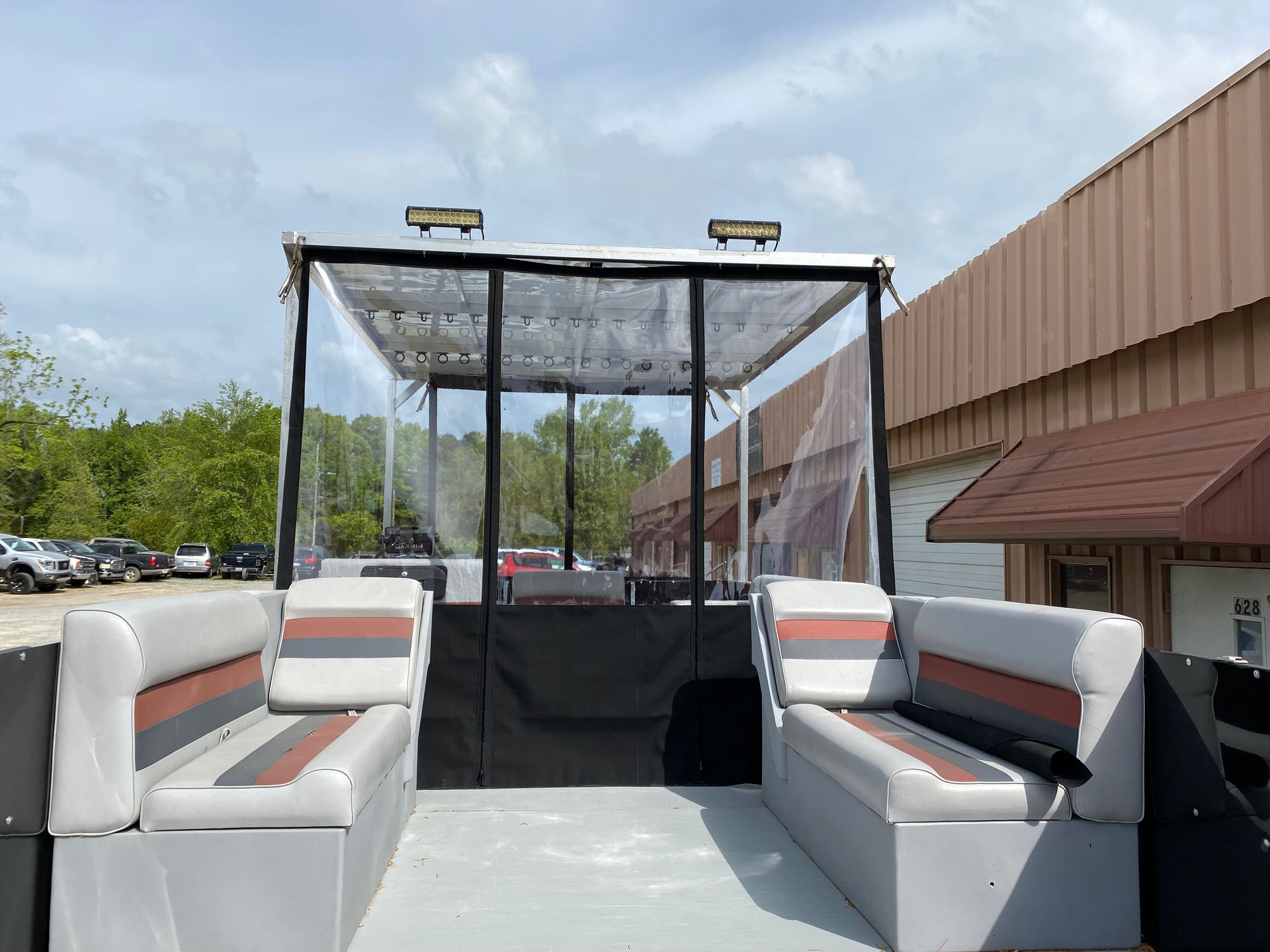 Open-air passenger cart with white benches and a black canopy beside a brown building