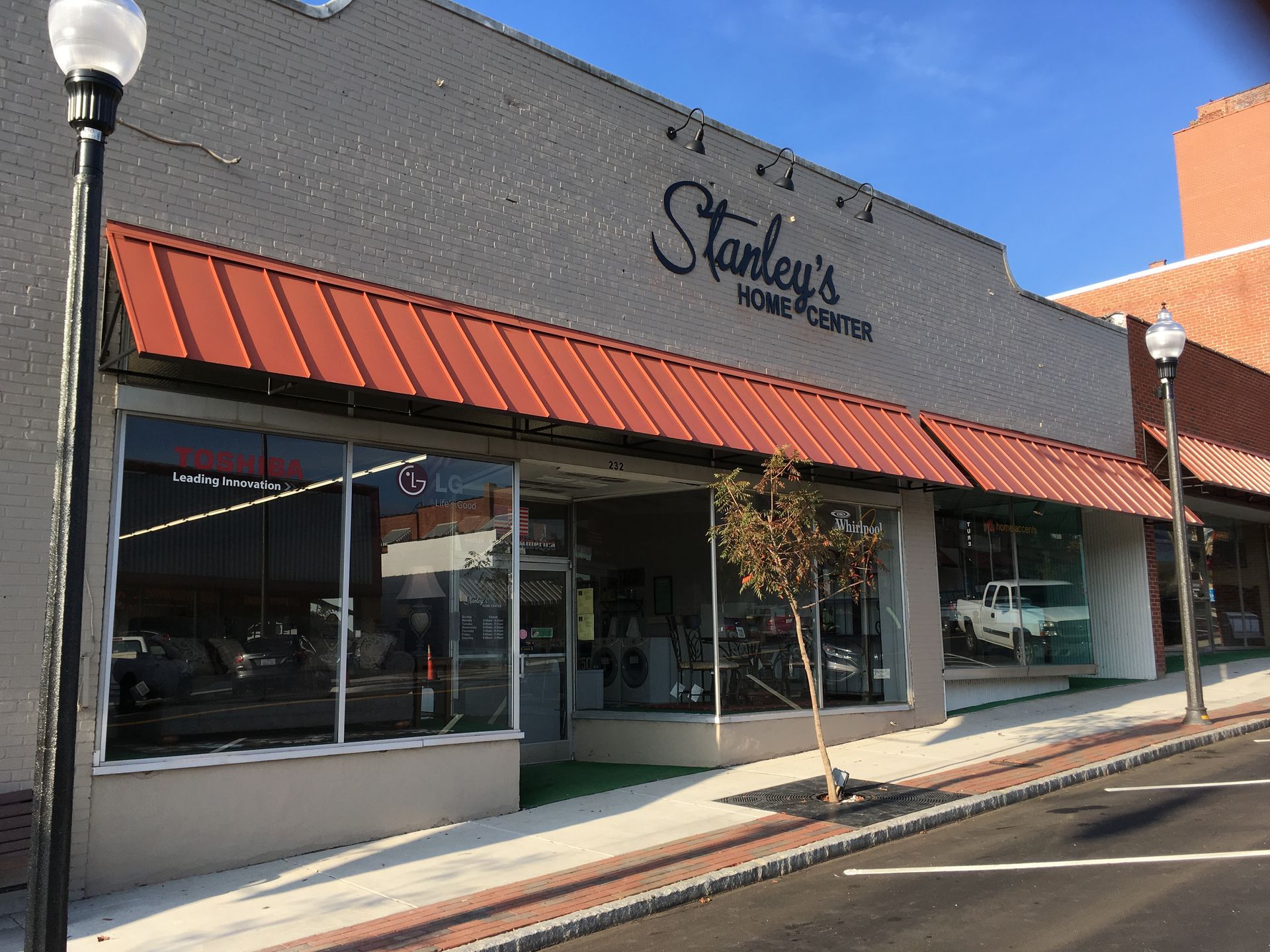 Storefront with red awning and large windows on a sunny street corner