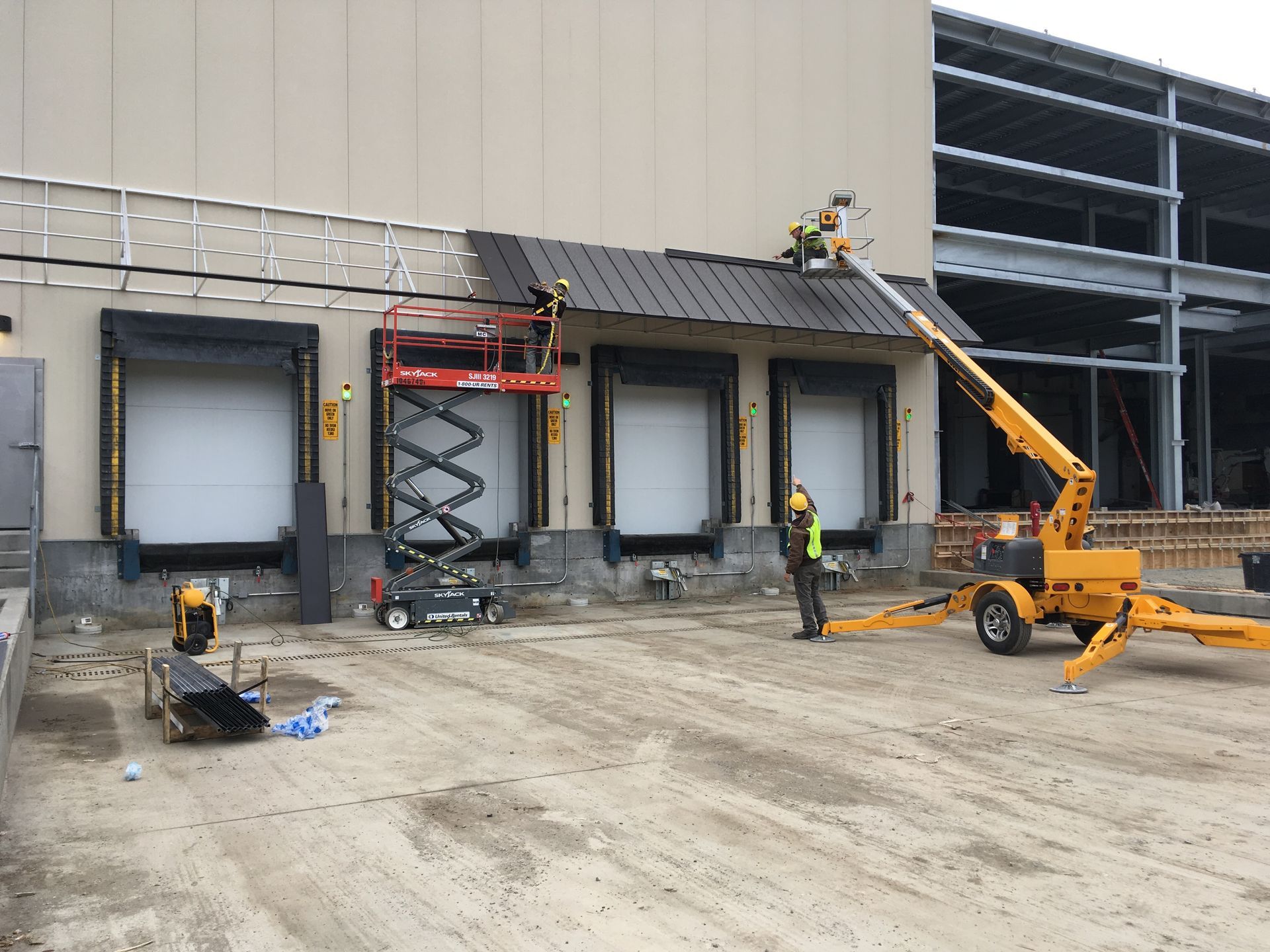 Construction workers and lifts at a warehouse loading dock under renovation