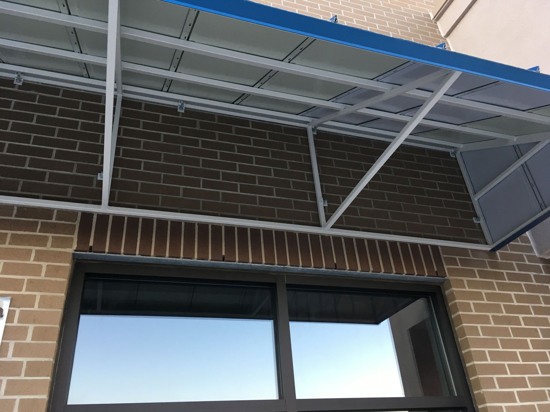 Brick building facade with a metal awning above a large window and open door frame