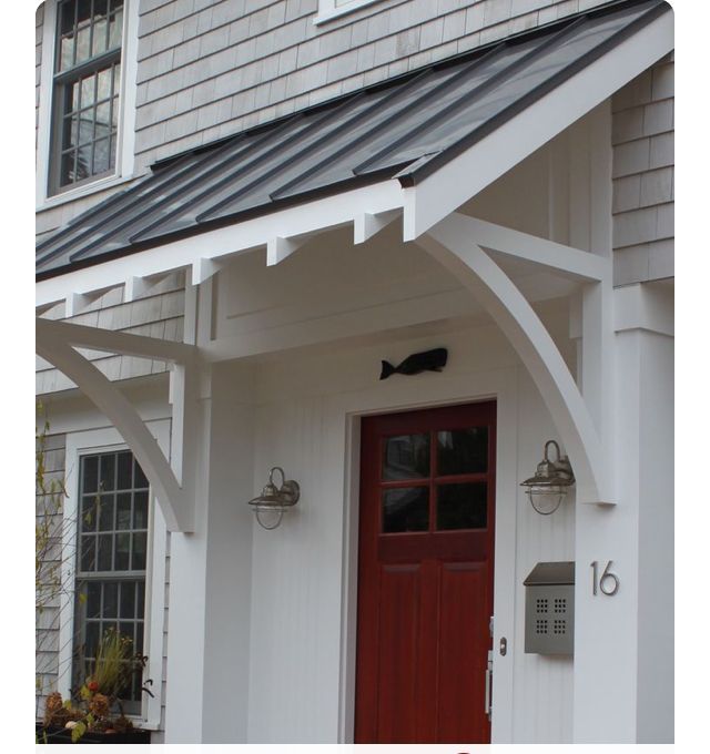 Red front door under a white porch with gray awning and house number 16 on the wall
