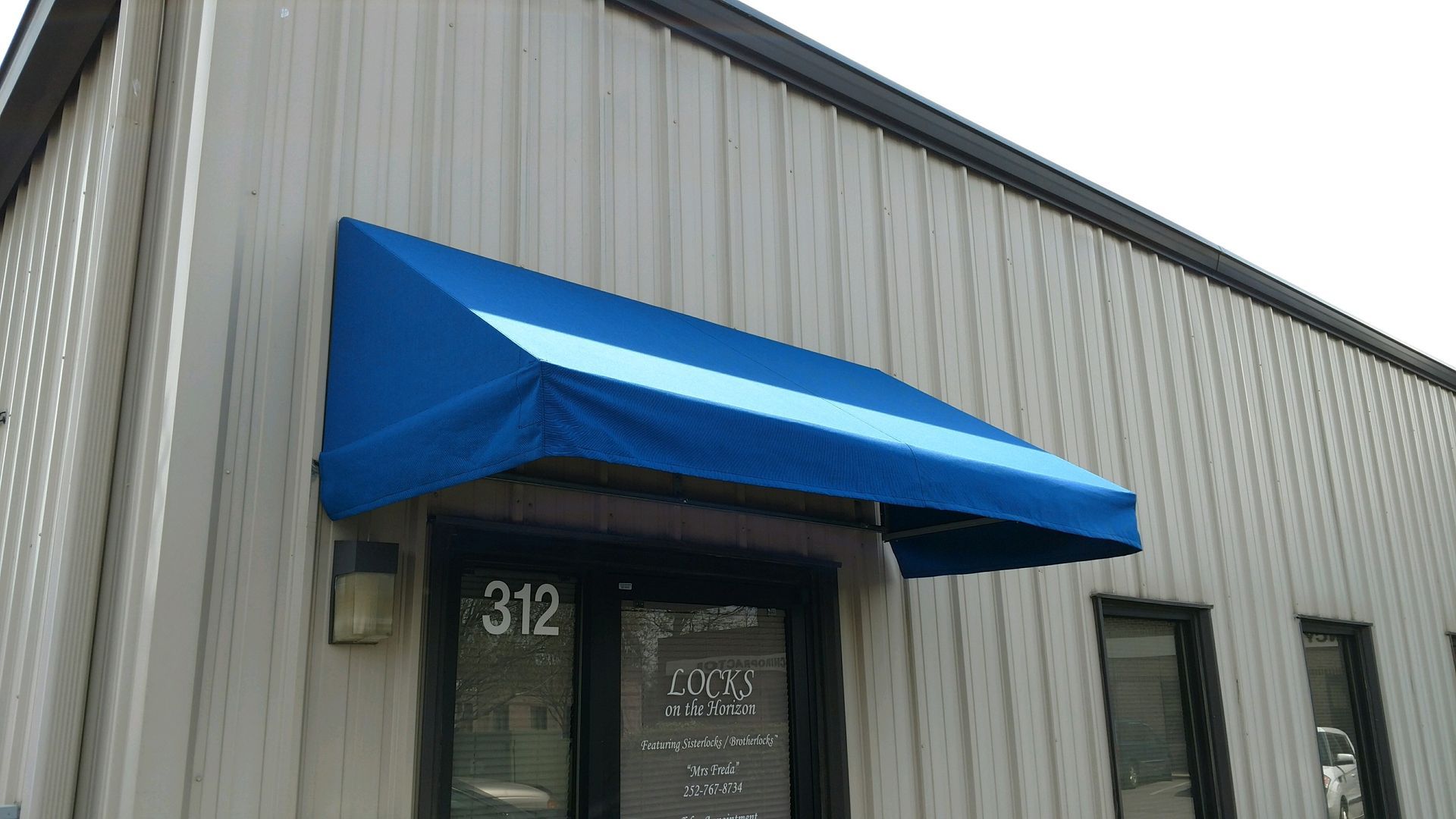 Blue awning over a building entrance with the number 312 on the door