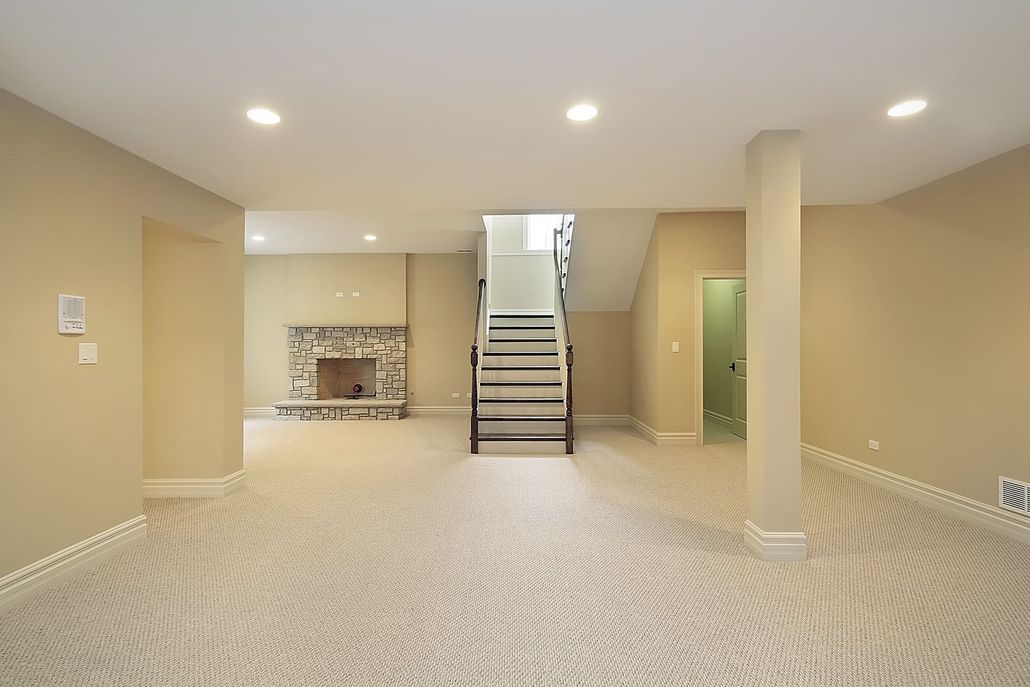 Basement with beige carpet, fireplace, stairs leading upwards, and recessed lighting.