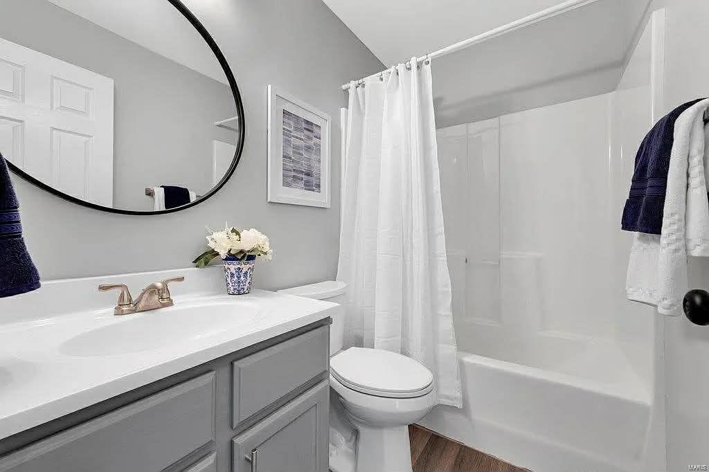 Bathroom with a wooden vanity, two white sinks, a tub, window, and a large mirror.