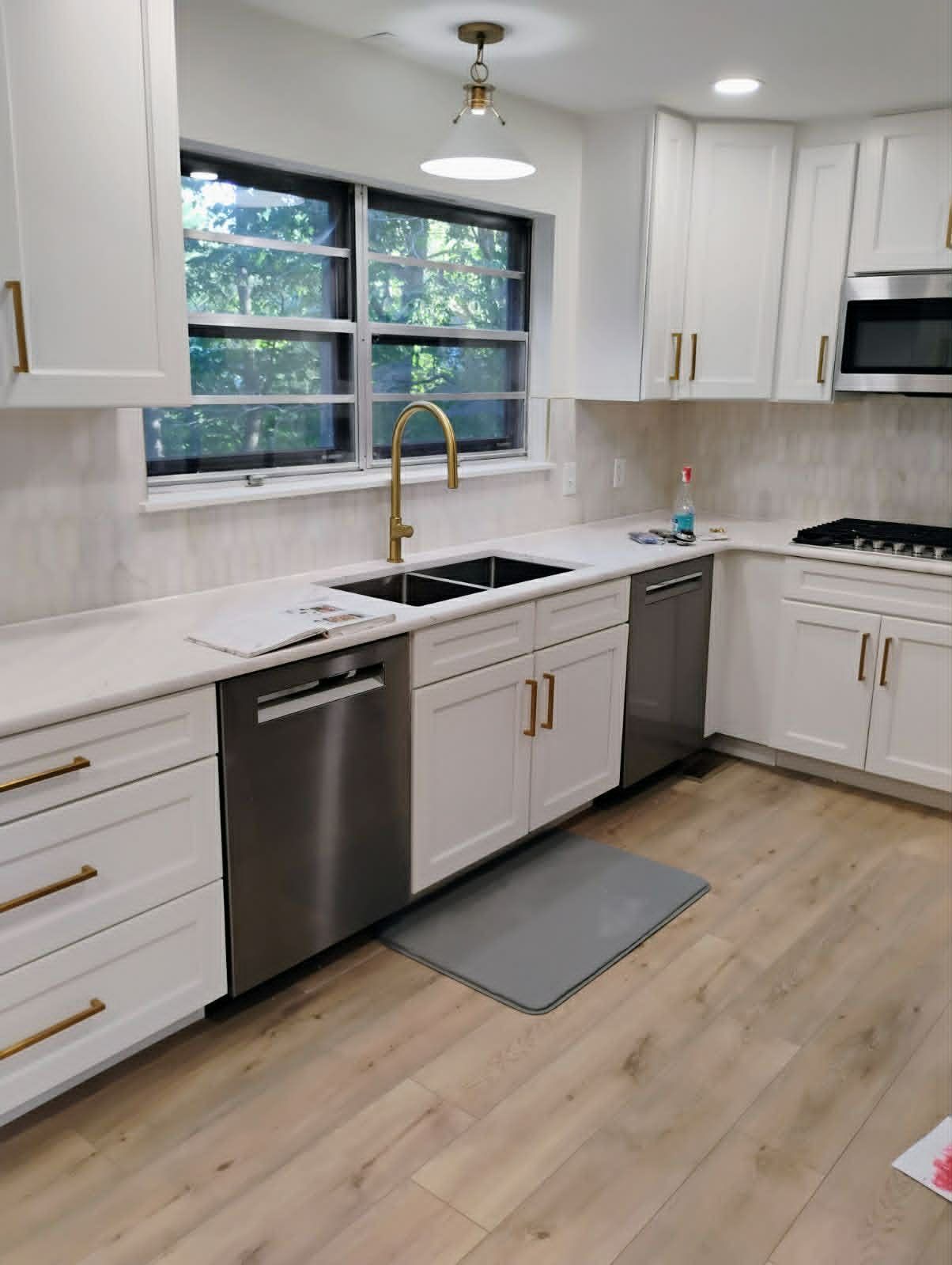 Newly renovated kitchen with white cabinets, stainless steel appliances, and gold hardware.