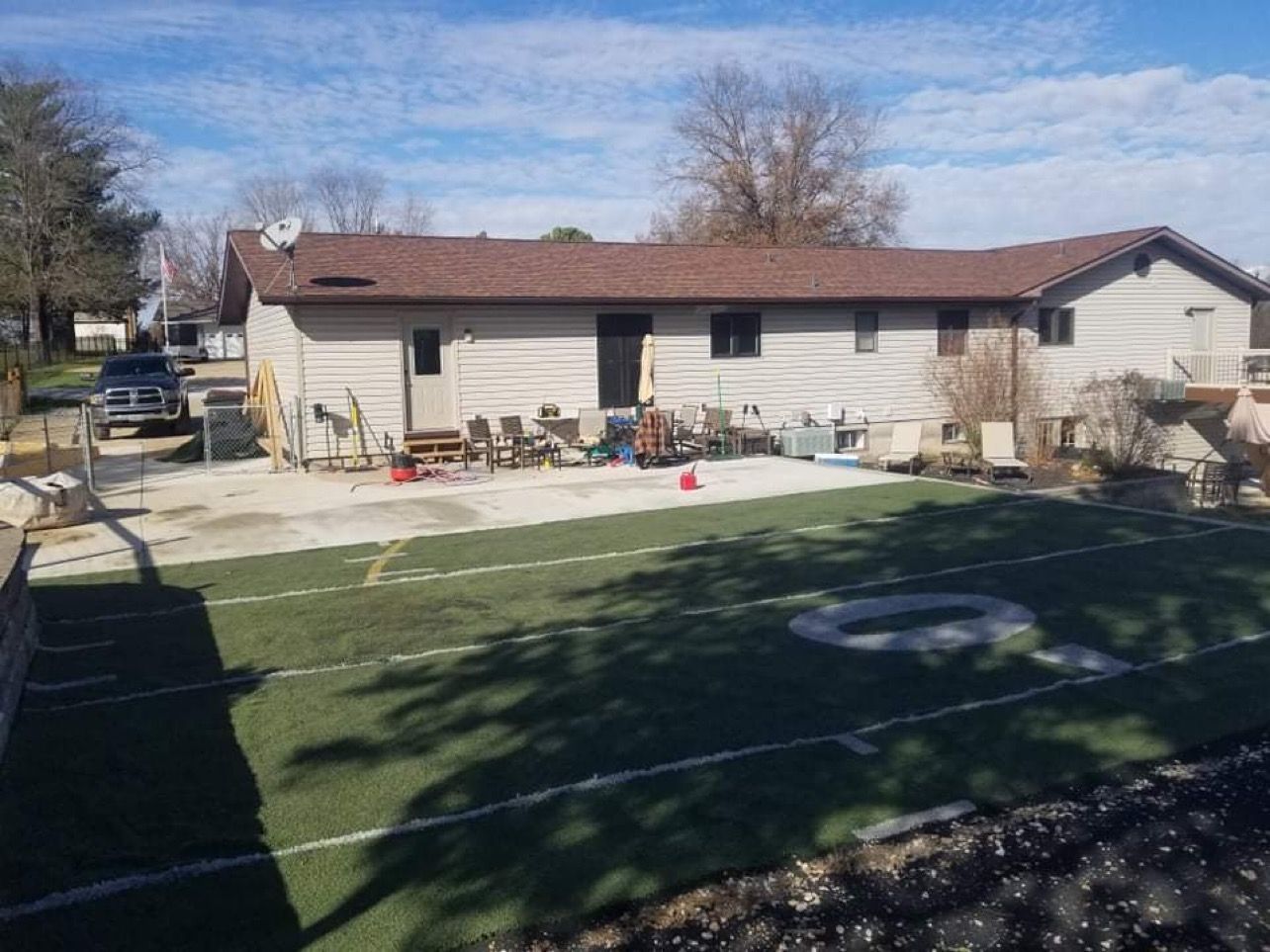 Backyard with a small building, a concrete patio, and a turf football field.