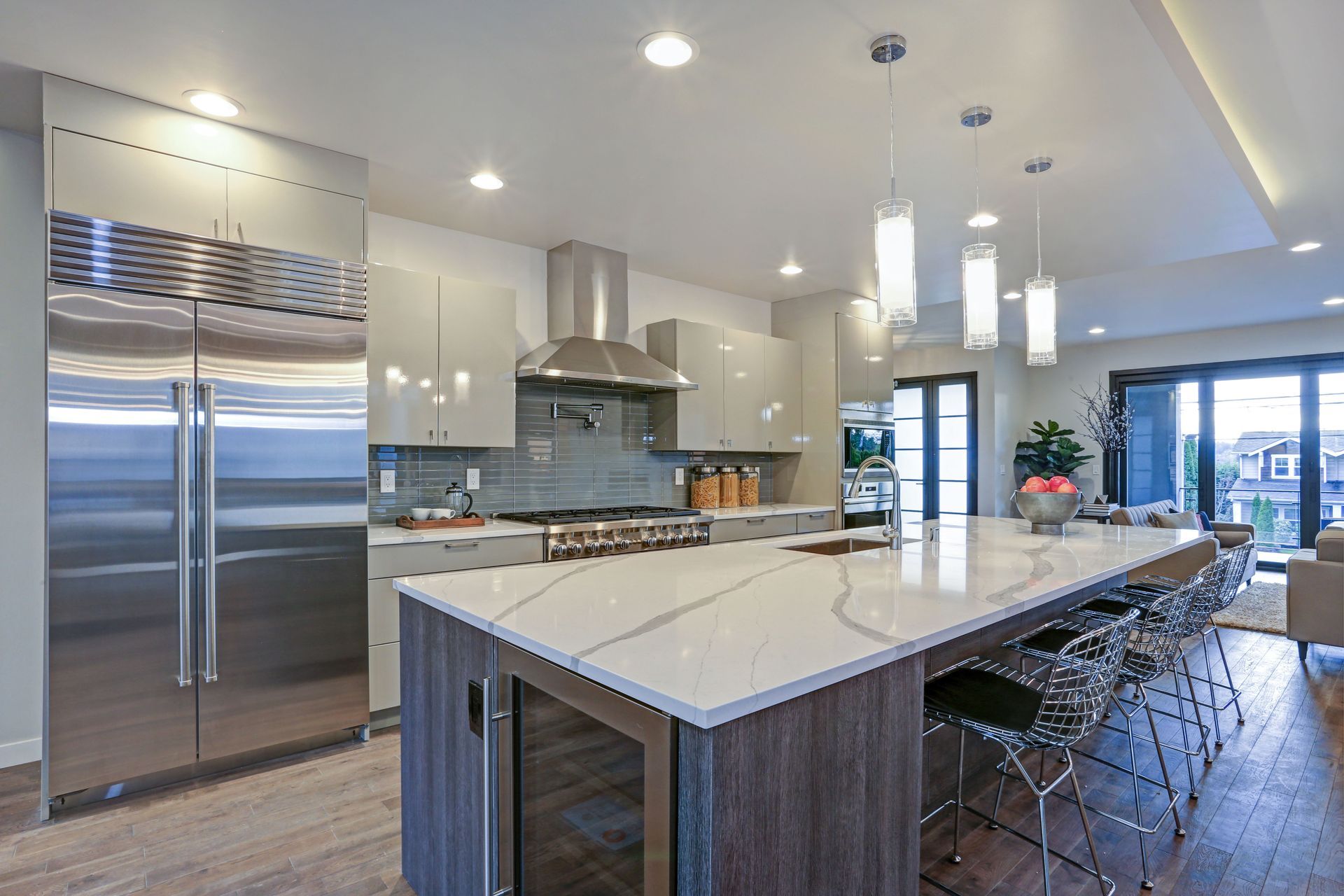 Modern kitchen with large island, stainless steel appliances, light cabinets, and bar seating.