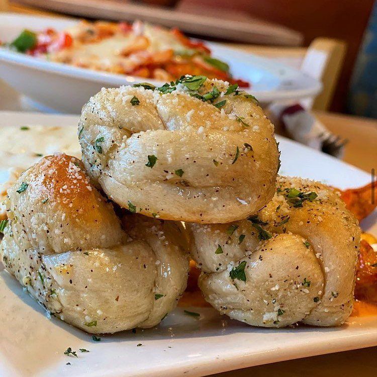 Garlic knots are stacked on top of each other on a white plate.